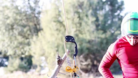 Climbing-yellow-and-black-carabiner-while-man-in-red-get-dressed-for-climbing-trees