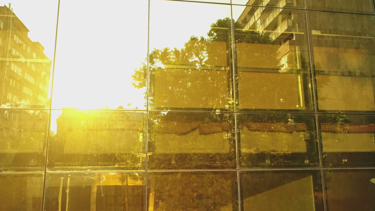 벽에 거울 창문이 있는 비즈니스 디스트릭트 빌딩이나 쇼핑몰의 4k 외관, 빛, 거울 벽에 있는 도시, 자동차 및 타워의 반사, 드론 카메라 이동