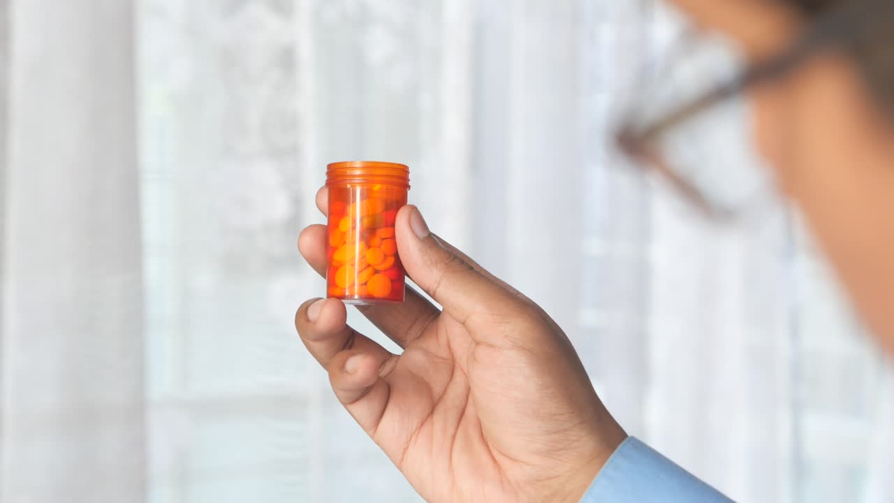 작은 오렌지색 약 병을 들고 있는 사람
