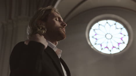 young caucasian man blessing himself in church