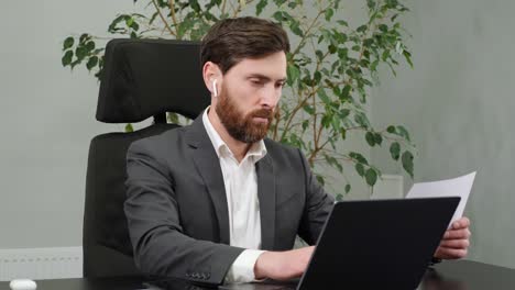 hombre de negocios enfocado trabajando en una computadora portátil sosteniendo documentos en la oficina. hombre profesional escribiendo en el teclado de la computadora portatil en el lugar de trabajo de la oficina. retrato de hombre de negocios confiado hace informes en el interior.