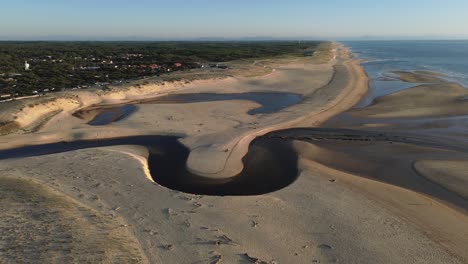 Mouth of the coastal river called Courant d'huchet in french and located on the coast of Southwestern France, in moliets commune. Aerial view during golden hour. Orbital move.
