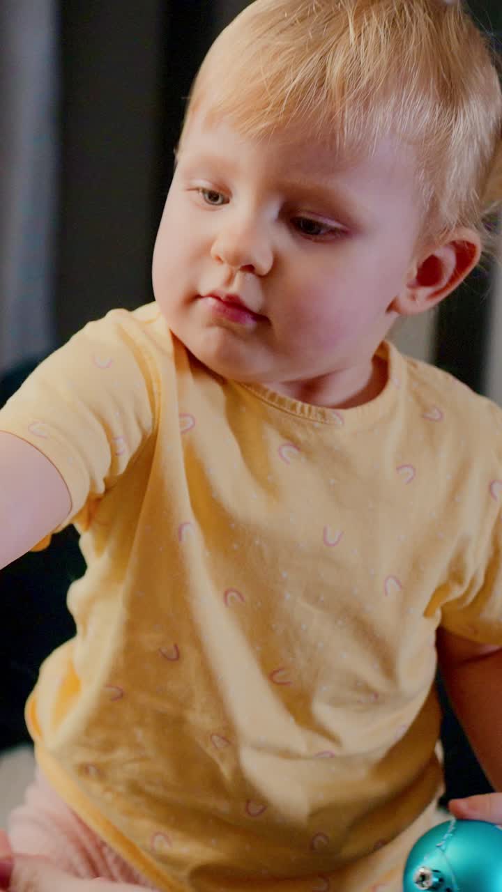A Curious Young Child With Blunt Bangs in a Yellow Top Captivated by a Colorful Toy, Displaying a Sweet Expression in a Cozy Indoor Setting, Radiating Playful Innocence and Wonder