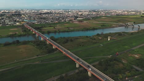 Drone-Shot-Of-Arakawa-River-In-Saitama,-Japan-With-Long-Road-Bridge-Spanning-Across---aerial