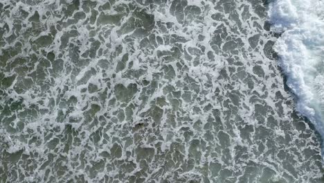 coastal rocks and waves crashing, erosion - daytime - aerial bird's eye view overhead shot