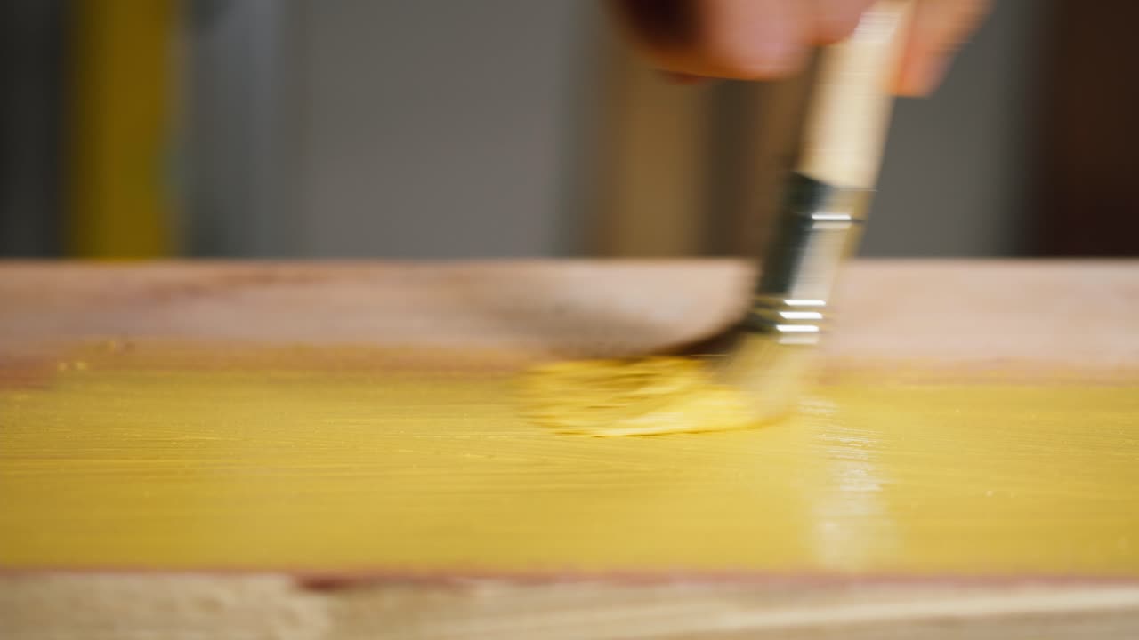 Dipingere una tavola di legno di giallo con un pennello