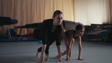 two young women practice gymnastics in a gym