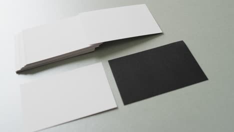 Close-up-of-blank-white-and-black-business-cards-on-grey-background,-copy-space,-slow-motion