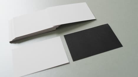 close up of blank white and black business cards on grey background, copy space, slow motion