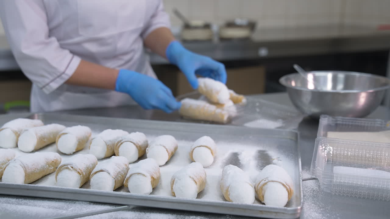 Delicious desserts packaging at the food factory. Confectionery worker puts a few cannoli cakes into plastic boxes. Close up.