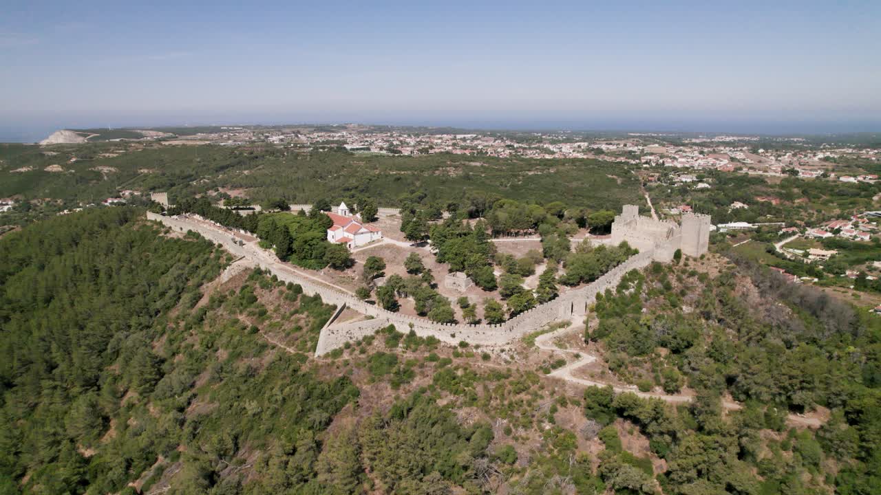 alto paralaje aéreo sobre la cima de la colina del castillo de sesimbra que revela la ciudad costera como fondo