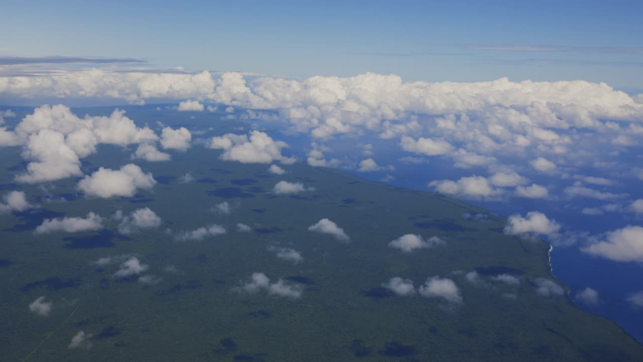una impresionante vista aérea desde un avión muestra una exuberante isla de bosque tropical rodeada de vastas nubes esponjosas en el cielo