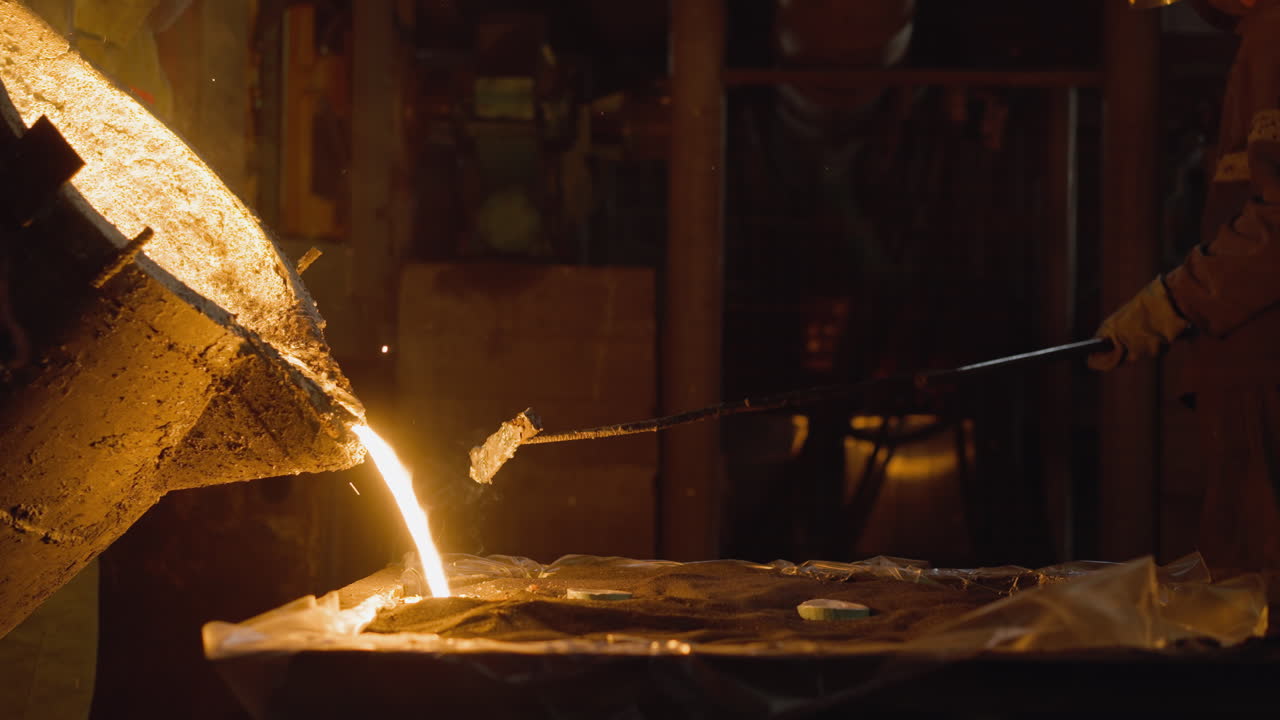 Foundry worker casting molten metal, with radiant spill from ladle