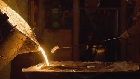 foundry worker casting molten metal, with radiant spill from ladle