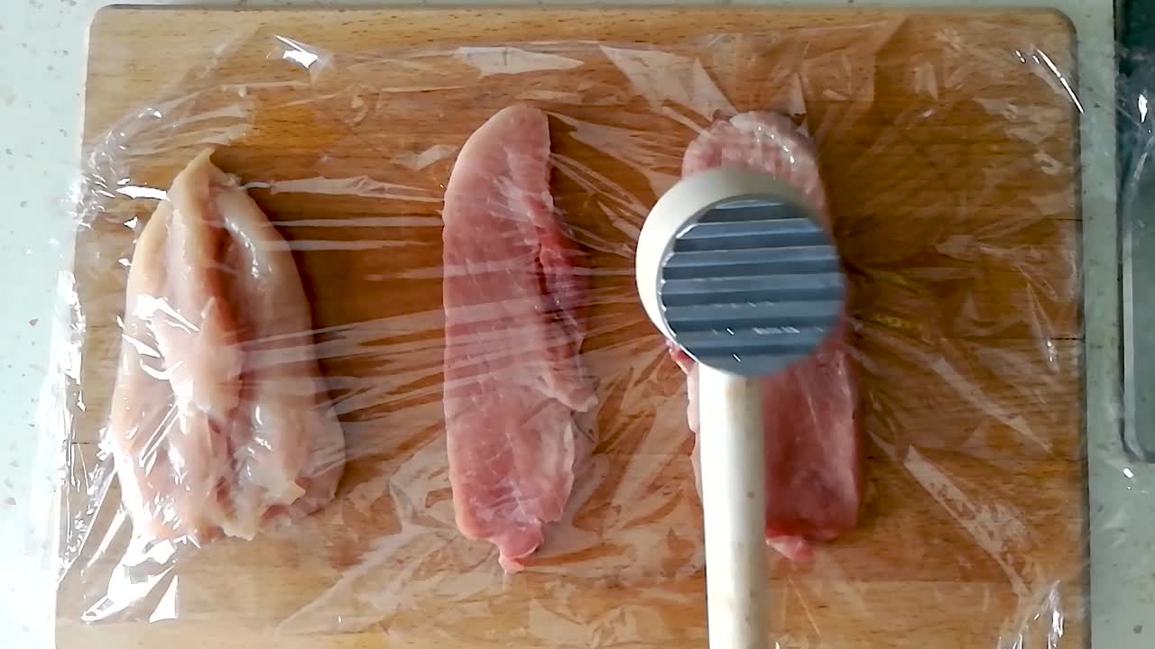 나무 커팅 보드, 오버헤드 슬로모에 달라붙는 필름을 통해 나무 고기 망치로 돼지 허리를 부드럽게 합니다.