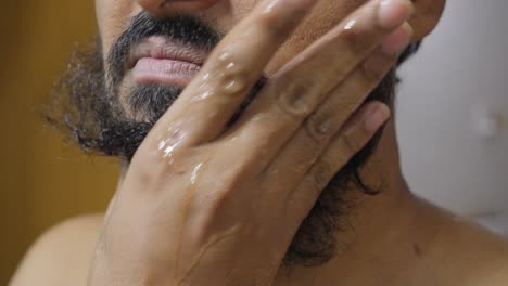 a close-up of a man with a beard gently washing it with soap, focusing on his hands and beard as the lather creates a clean, soft texture