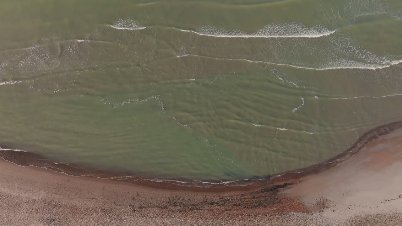 vista aérea verdosa o, en otras palabras, agua de mar en flor lava la arena de la playa a principios de la mañana de otoño