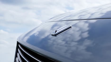 Close-up of a luxury car&#039;s hood ornament against a cloudy sky