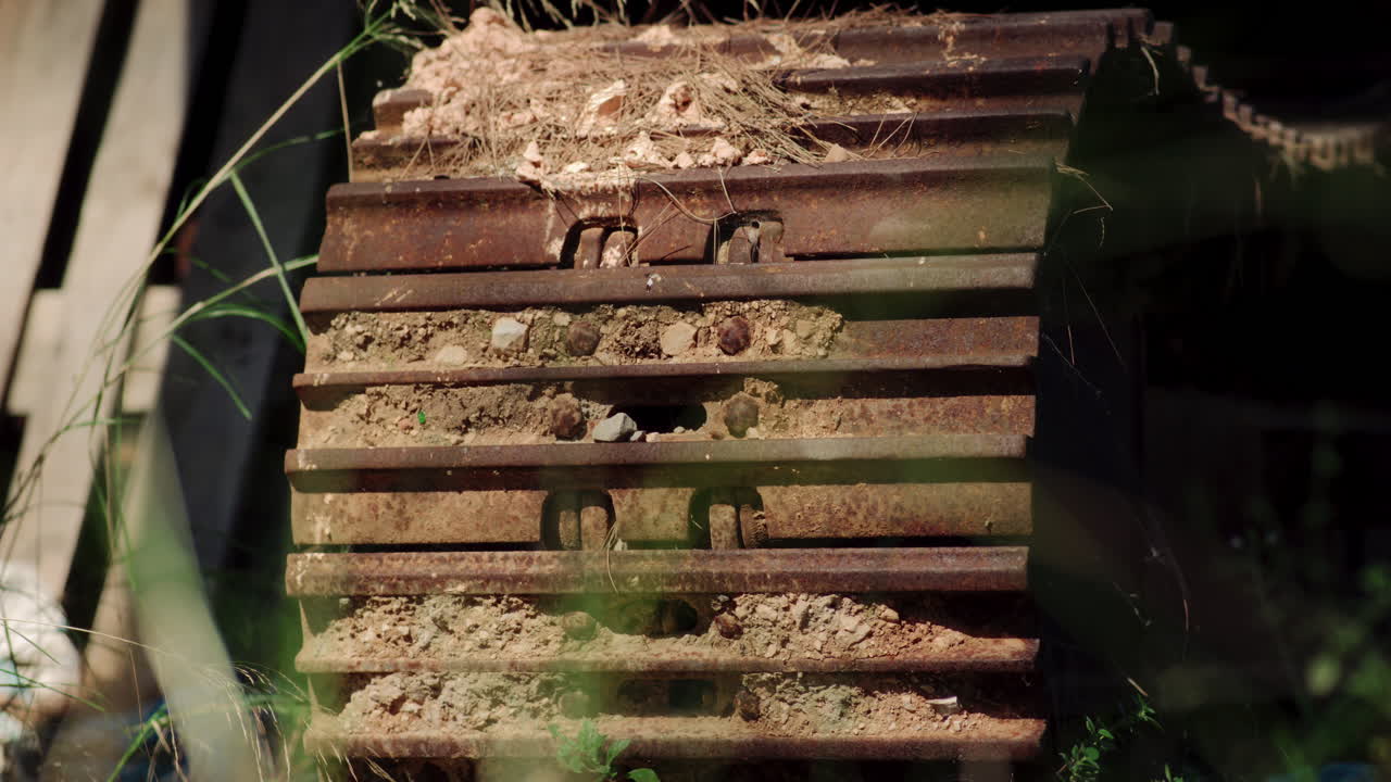 그늘이 무거운 기계에 춤을 춘다. 건조한 진과 풀로 인 트랙 바.