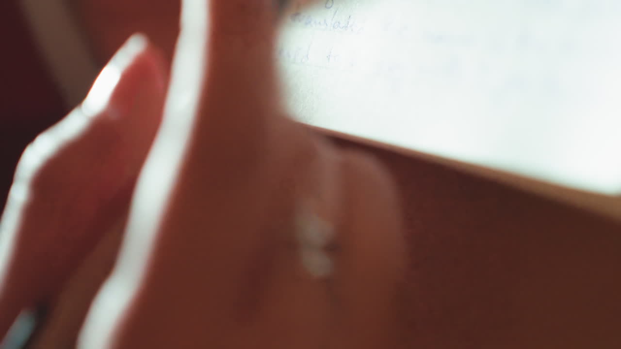 Primo piano di una mano che scrive su un taccuino, con una luce fresca e ombreggiata. Punta affilata della penna, anelli d'argento al dito, appunti concentrati, modifiche ai margini e stesura di una lista di controllo, consistenza tattile della carta, studio notturno.