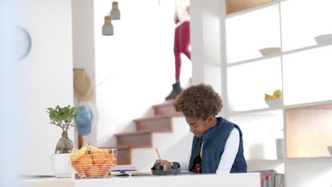african american boy sitting at table and doing homework, slow motion
