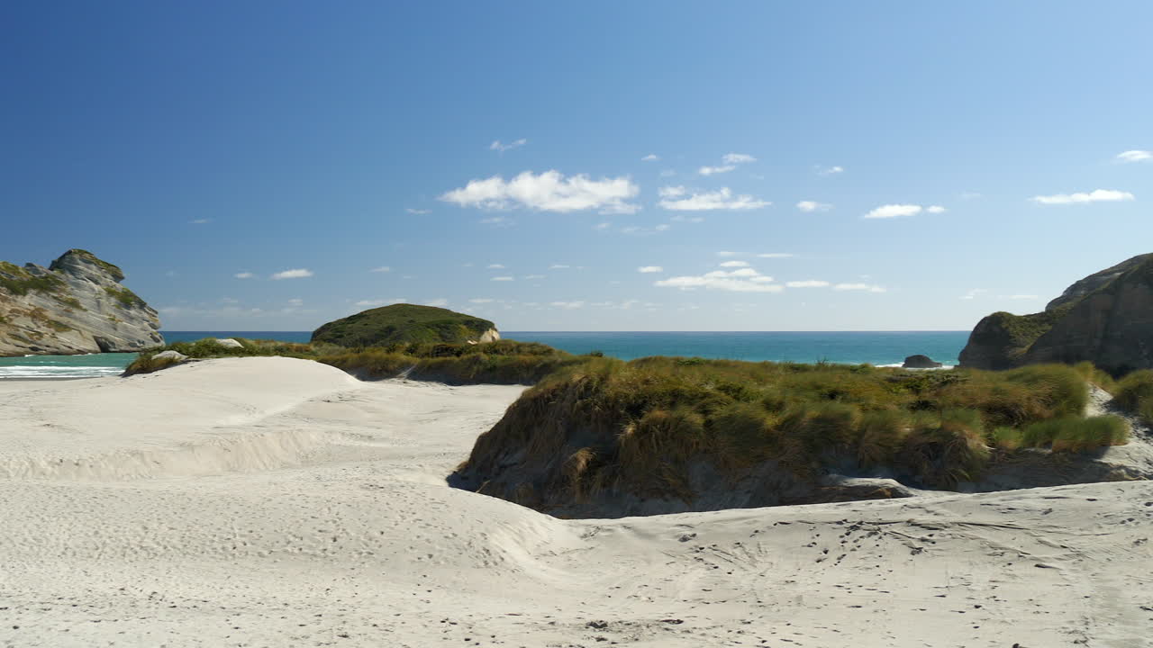People exploring Whareriki Beach, South Island of New Zealand on sunny, summer day.