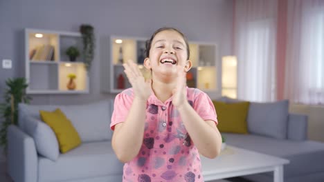 una niña aplaudiendo emocionada a la cámara.