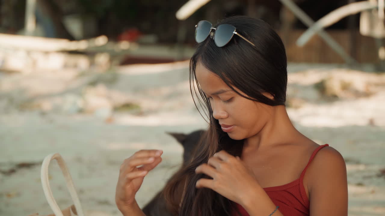 Giovane donna seduta su una spiaggia sabbiosa, ritratto estivo rilassato con occhiali da sole, borsa intrecciata e lunghi capelli mossi dalla brezza calda, espressione pensierosa, luce dorata soffusa, sfondo di un'isola tropicale, prendisole casual
