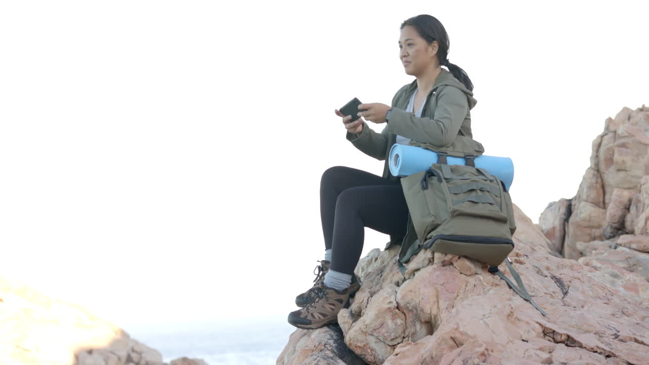 Hiking on mountain, woman taking photo with smartphone, backpack and yoga mat, copy space