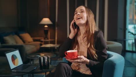 smiing woman calling mobile in hotel lounge. business woman talking smartphone