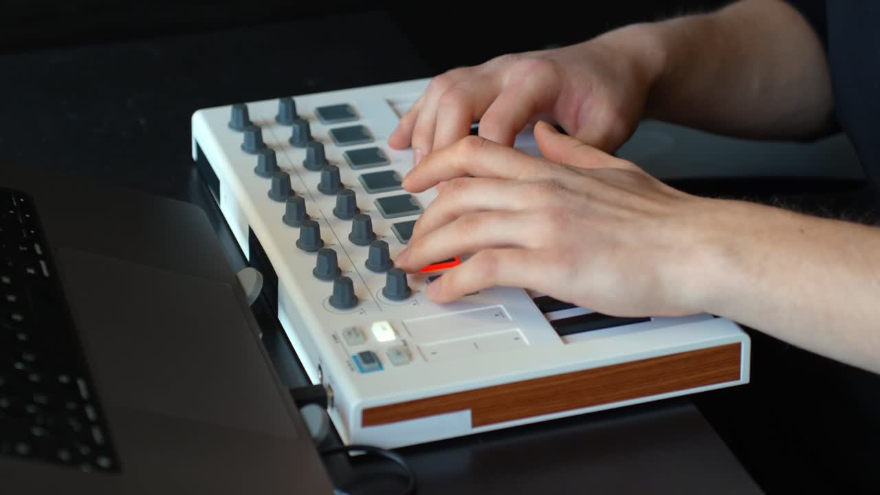 Music producer's hands tapping the pads of a MIDI pad controller to record drums and percussion for electronic music production, with hythmic workflow of beat making in home studio, extreme close-up