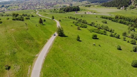 El-Coche-Conduce-Por-Una-Carretera-Rural-A-Través-De-Verdes-Pastos-De-Verano,-Paisaje-De-Pradera-Polaca