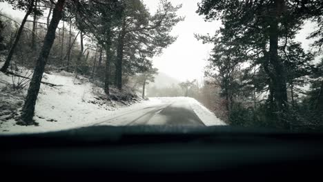view from car front window on snowy road in winter scenery at snowfall