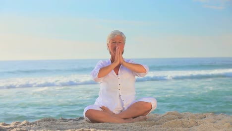mujer haciendo yoga en una playa