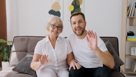 Feliz-Madre-Con-Su-Hijo-Saludando,-Hablando-Y-Riendo-Juntos-En-Una-Videollamada-Mientras-Se-Sienta-En-El-Sofá-En-La-Sala-De-Estar-Y-Mira-La-Cámara