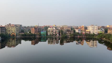 rows of old buildings or apartments beside a pond in kolkata, india