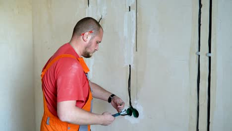 electrician with pliers cleaning wires in junction box for socket