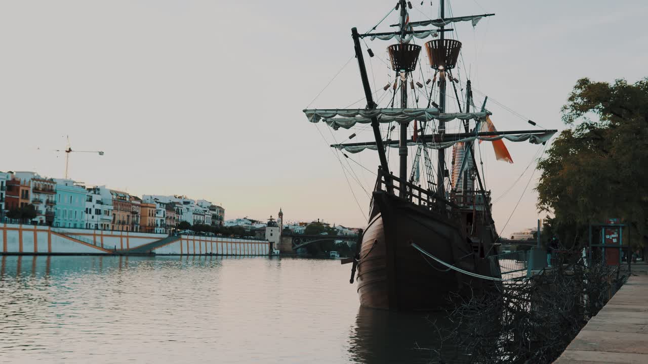 Sunset sailing ship made of wood, pirate ship of the middle ages next to a river in a beautiful Spanish city