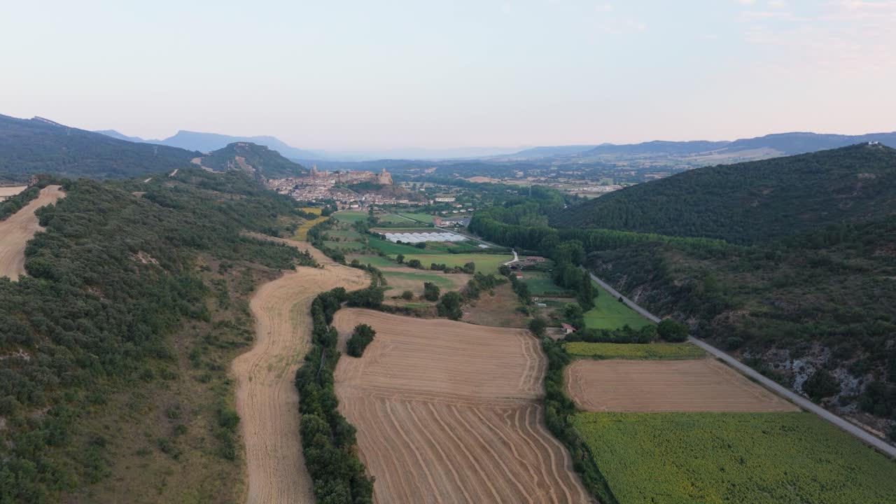 Approaching drone shot of a hillside village and its surrounding farmlands in a Spanish countryside in Valderama, Burgos province in Spain.
