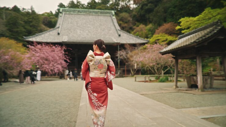 Donna in kimono a un tempio con alberi di ciliegio in fiore
