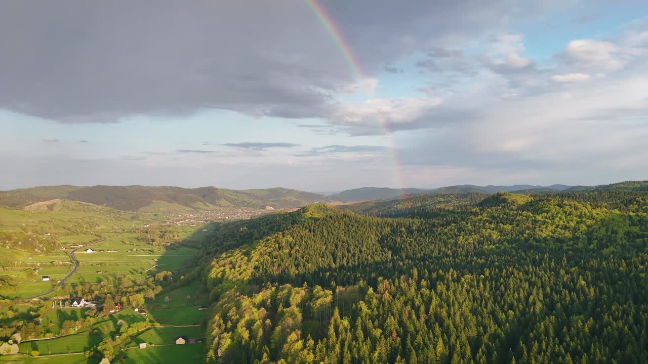 Drone video of forested valley between Poiana Micului and Manastirea Humorului, Romania, at sunset with a rainbow