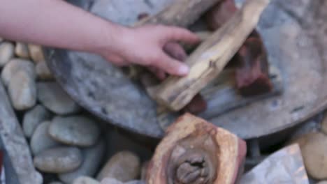 man places wood on a fire for a barbeque