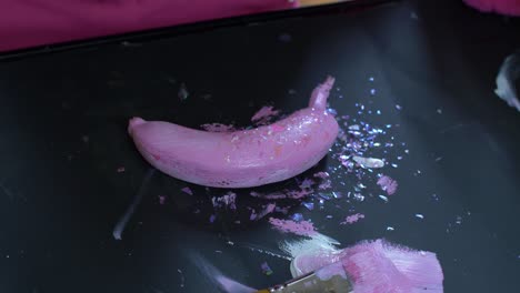 putting glitter on a pink painted banana, closer shot