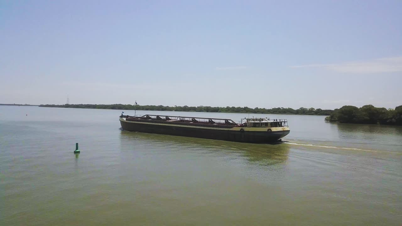 브라질의 강에 있는 화물선, 선박이 하류로 이동할 때 낮은 공중 팬