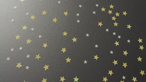 Video-of-multiple-gold-and-silver-stars-scattered-on-black-background