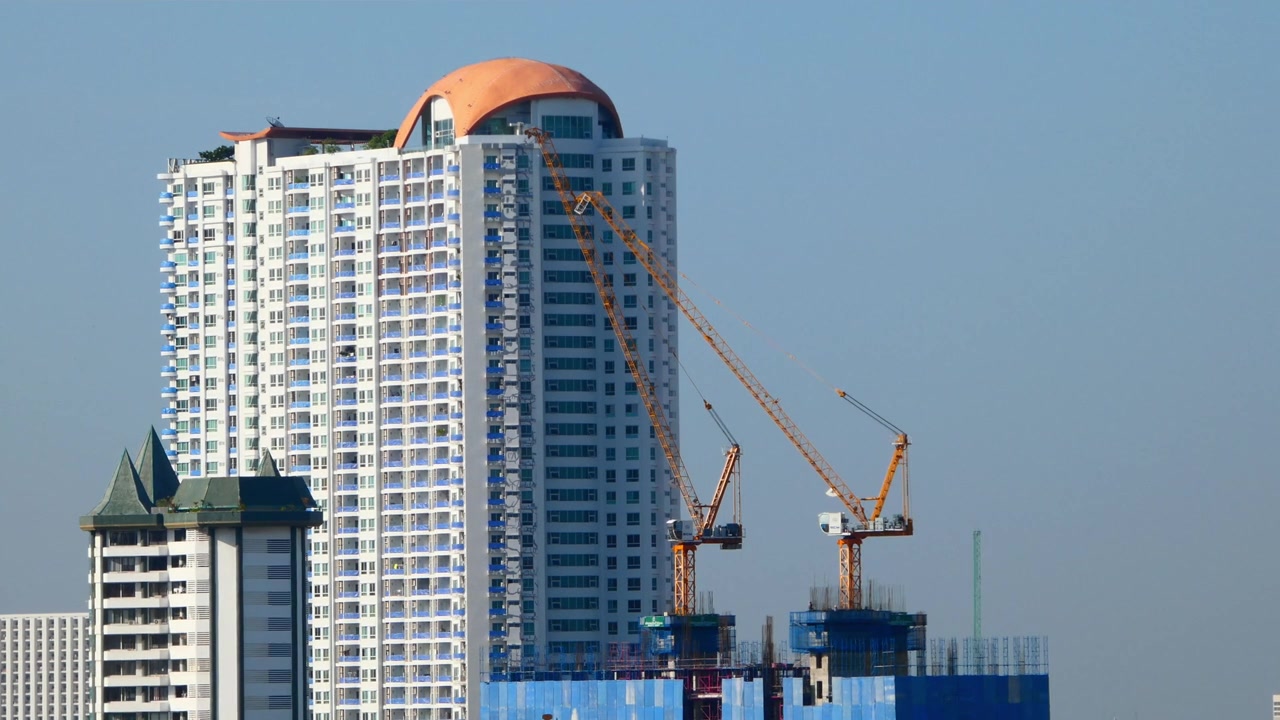 Timelapse de una grúa torre operando en una obra de construcción urbana, capturando el progreso continuo de la edificación y el desarrollo de la ciudad moderna