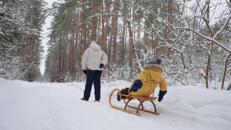 Kleines-Kind-Sitzt-Im-Schlitten,-Als-Seine-Mutter-Es-über-Den-Klaren-Schnee-Im-Wald-Zieht