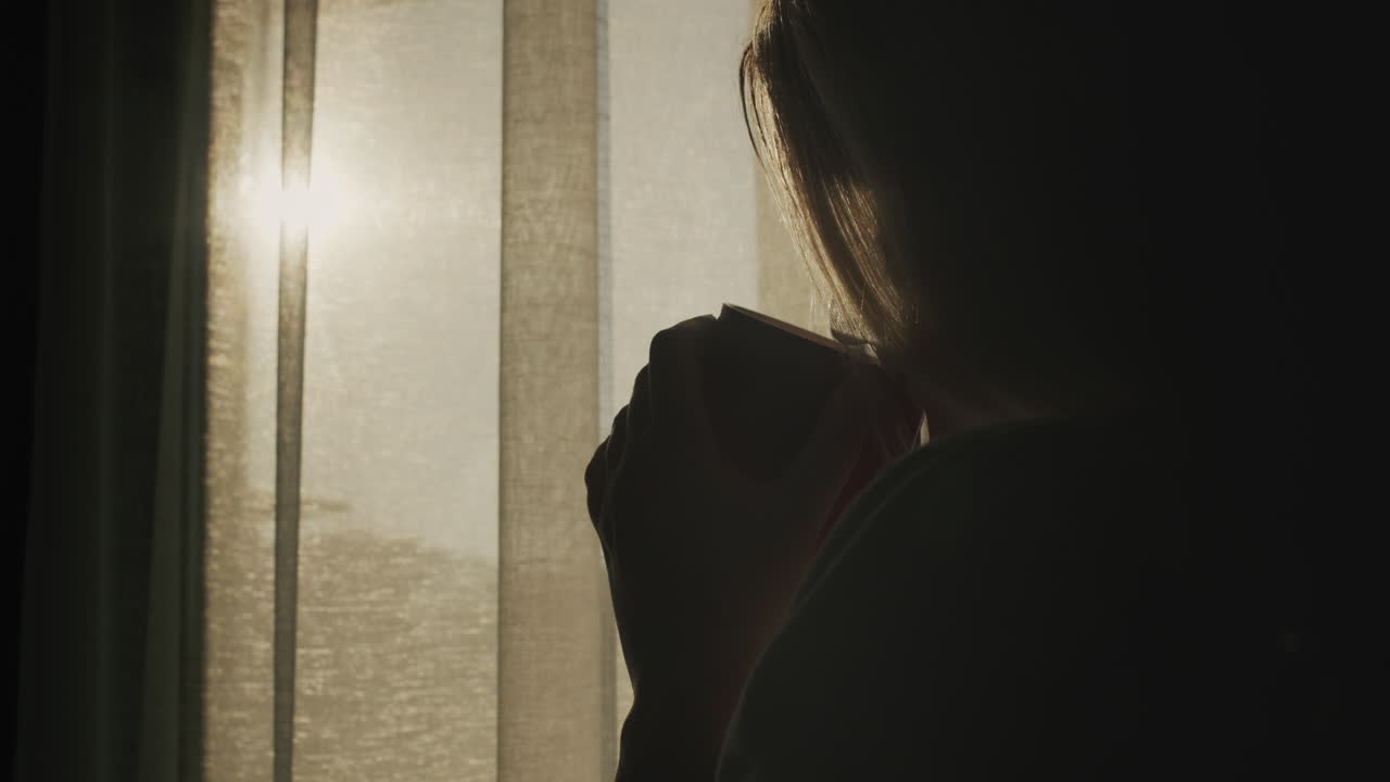 뒷면: 뜨거운 차 한 잔 을 들고 있는 여자 가 태양 이 뜨는 창밖 을 바라보고 있다. 뜨거운 음료 와 좋은 기분