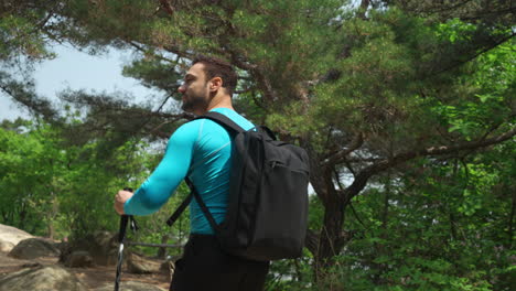 Athletic-Hiker-man-with-a-backpack-and-trekking-poles-walks-through-a-pine-forest-in-korean-mountains