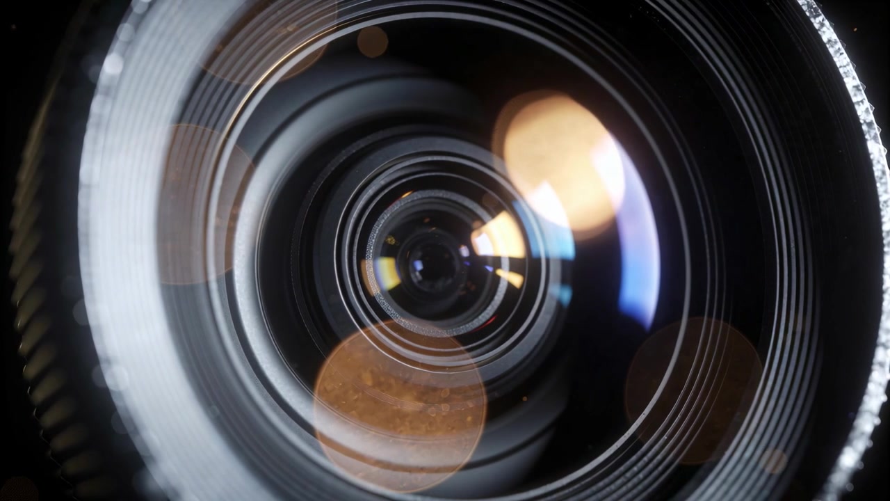 Trækker sig tilbage, stort objektiv roterer, afslører belagte ringe, riflet ring, varme bokeh-glød i studie.